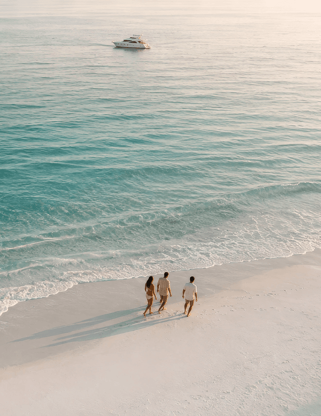 Couple walking along a pristine white sand beach with turquoise water